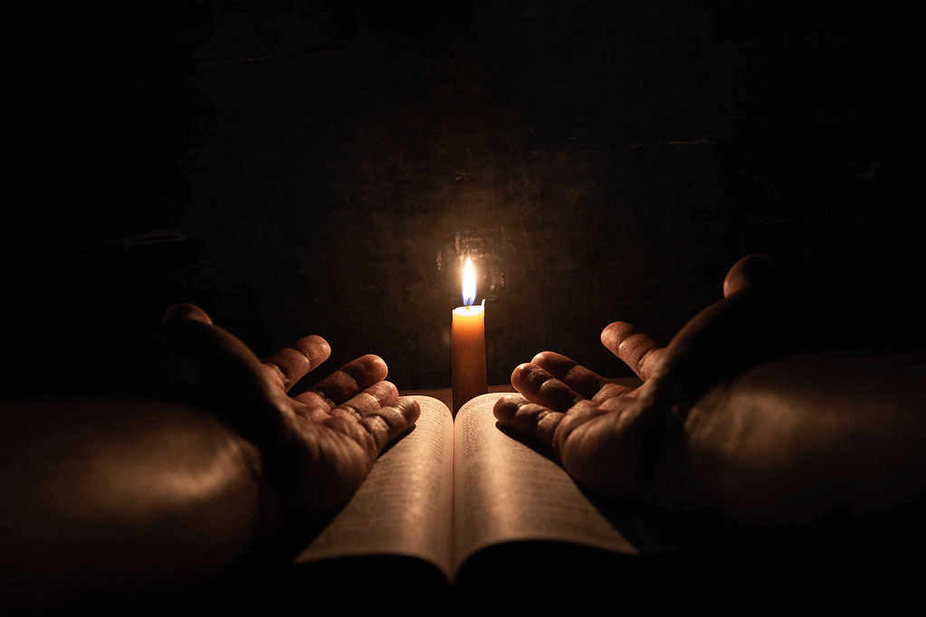 Prayer Request. Two hands praying with the bible and candle